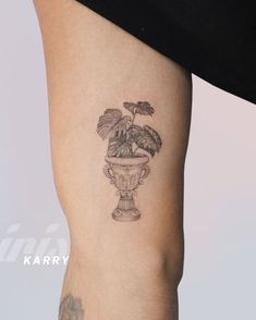 a tattoo on the leg of a woman with a potted plant in it's center