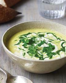 a white bowl filled with soup and garnished with parsley next to bread