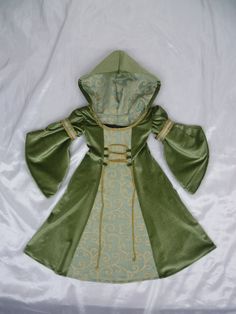 a green and gold dress on a white sheet with a hoodie over the shoulders