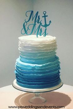 a blue and white wedding cake with the word mr and mrs on top is sitting on a table