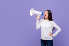 a young woman holding a megaphone up to her face and shouting into the air