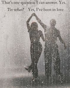 two people are dancing in the rain with their hands behind their backs as they stand under an umbrella