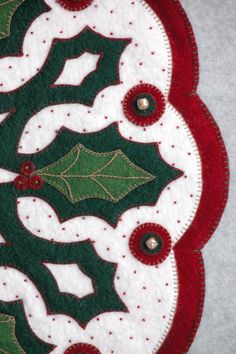 a close up of a christmas decoration with holly leaves and red berries on white fabric