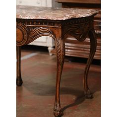 an ornate wooden table with marble top in a living room or dining room, next to a bench