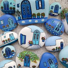 blue and white painted rocks with windows and flowers on them are arranged in the shape of houses