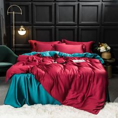 a bed with red and teal sheets in a dark room next to a green chair