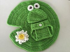 a crocheted green frog hat and diaper cover with a flower on it