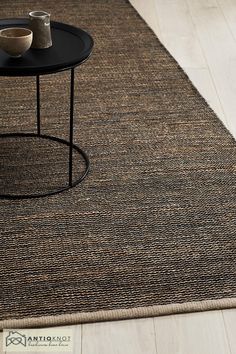 a coffee table with two cups on top of it next to a rug that looks like woven fabric