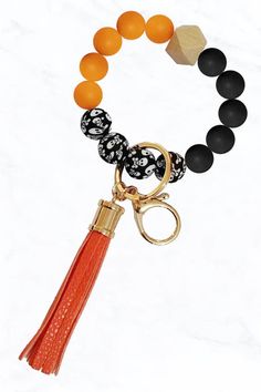 an orange and black beaded bracelet with a tasseled charm hanging from it