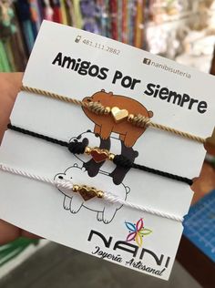 two bracelets with gold hearts and bears on them are shown in front of a store display