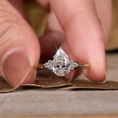 a close up of a person's hand holding a ring with a diamond on it