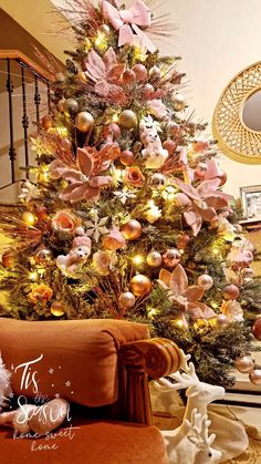 a decorated christmas tree in a living room with pink and gold ornaments on the top