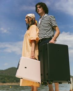 a man and woman standing next to each other holding suitcases