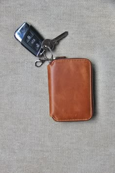 a wallet with a keychain attached to it sitting next to a cell phone