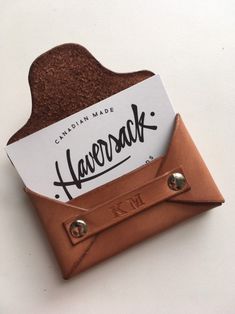 a leather wallet with a name tag attached to the card holder that is holding an envelope