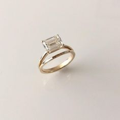 an engagement ring with a baguette cut diamond in the center, on a white surface