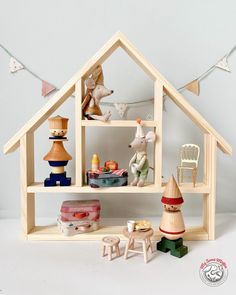 a wooden doll house with toys and decorations on the shelf, including a toy mouse