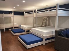 bunk beds are lined up in a room with blue and white sheets on the mattresses