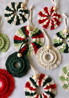 several ornaments are laid out on a white tablecloth with green, red and white yarn