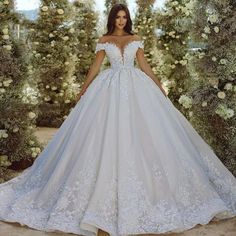 a woman in a white wedding dress standing next to an archway with flowers on it