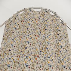 a curtain with flowers on it hanging from a metal rod in front of a white wall