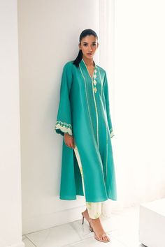 A long turqouise front open rawsilk kurta features printed applique and pleated details. Adorned with delicate embroidery on scalloped sleeves, the kurta is paired with a floral printed rawsilk shalwar. Model Height is 5'7 and Shirt length is 48" Festive Lawn Suit With Embroidered Long Sleeves, Festive Long Sleeve Lawn Suit With Embroidered Sleeves, Transitional Long Sleeve Silk Lawn Suit, Designer Long Sleeve Kurta For Summer, Designer Long Sleeve Summer Kurta, Cotton Silk Kurta With Embroidered Sleeves, Anarkali Cotton Silk Kurta With Embroidered Sleeves, Traditional Spring Salwar Kameez With Embroidered Sleeves, Spring Silk Kurta With Embroidered Sleeves