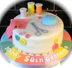 a birthday cake decorated with buttons and sewing needles