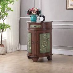 a small wooden cabinet with flowers on top and a clock sitting on it's side