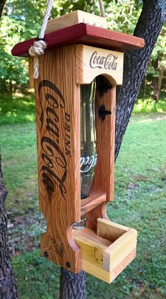 a wooden bird feeder hanging from a tree