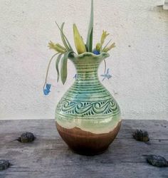 a green and brown vase sitting on top of a wooden table