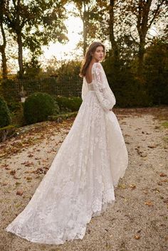 a woman in a wedding dress standing on gravel