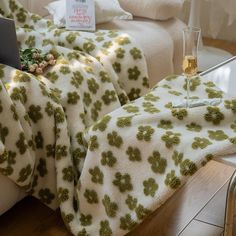 a couch covered in blankets with a glass of wine sitting on top of it next to a laptop computer