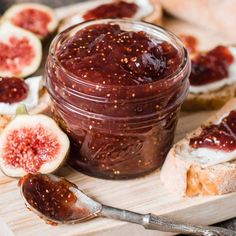 figs and bread on a cutting board with jam in a jar next to it