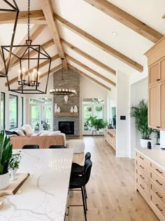 a large open concept kitchen and living room with wood beams, white marble countertops and wooden flooring