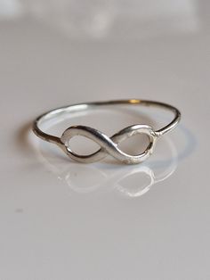 "Introducing our timeless Simple Silver Infinity Ring, designed to symbolize an everlasting bond and endless love. This elegant piece features a delicate infinity symbol, intricately crafted from high-quality 925 sterling silver. The sleek, continuous lines of the infinity loop gracefully embrace the band, creating a harmonious blend of sophistication and minimalism. Its lightweight and comfortable fit make it perfect for everyday wear or special occasions. Show your eternal affection with this Adjustable Infinity Ring For Mother's Day, Classic Adjustable Infinity Stackable Rings, Mother's Day Infinity Adjustable Rings, Dainty Infinity Stackable Rings For Gift, Dainty Infinity Stackable Rings As Gift, Minimalist Infinity Ring As Gift, Minimalist Infinity Rings As Gifts, Adjustable Infinity Stackable Rings, Silver Infinity Promise Ring