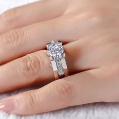 a woman's hand with a diamond ring on top of her finger and the other hand holding it