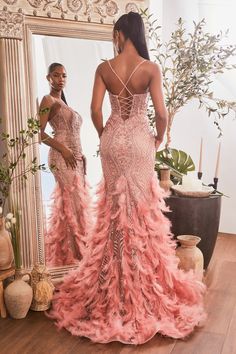 two women standing in front of a mirror, one wearing a pink dress with feathers on it