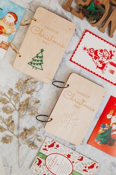 some christmas cards are laying out on a marble counter top next to a wooden ornament