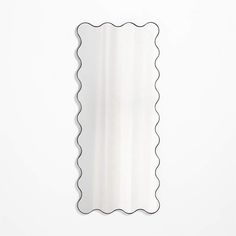 a mirror with scalloped edges on a white wall in the shape of a rectangle