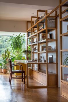 a wooden desk sitting in front of a window next to a book shelf filled with books