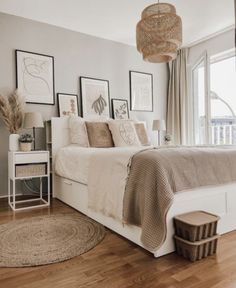 a white bed sitting in a bedroom next to a window with pictures on the wall