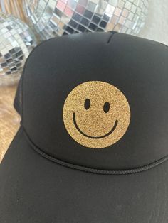 Product Description: Loving the trucker hat trend? We have you covered! Great for throwing on and heading out the door when you want to be trendy without a lot of effort. Gold Happy Face Quick Product Details and Features: Mesh back with adjustable snapback closure. Embroidered letters. Lightweight + Comfortable Product Fit: One size fits most. Product Care: Hand wash for spot care and let air dry. Shop Rooted and Free Notes: We offer free shipping on all orders $100 and over. We also offer free Trendy Trucker Hat With Letter Print And Flat Brim, Trendy Flat Brim Trucker Hat With Letter Print, Casual Snapback Hat For Party, Trendy Letter Print Flat Brim Trucker Hat, Fun Letter Print Baseball Cap With Flat Bill, Fun Flat Bill Baseball Cap With Letter Print, Fun Snapback Trucker Hat For Streetwear, Trendy Black Trucker Hat For Party, Fun Letter Print Flat Bill Baseball Cap