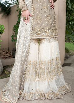 Pakistani designer embroidered white gharara dress White And Golden Dress Pakistani, Beige Bridal Dress, Silver Bride Dress, Net Sharara Designs, Heavy Wedding Dress, White Gharara, Gharara Dress, Bridal Gharara, Embellished Sleeves