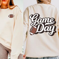 Get ready for football season in style in our trendy and cozy Game Day Sweatshirt. This cozy fall essential features a football printed on the front and Game Day displayed across the back. Whether you're cheering from the stands or enjoying the game at home, this comfort colors sweatshirt is perfect to cheer on your favorite team. Makes great group photos too!  This custom crewneck sweatshirt brings both incredible quality and amazing style to the mix. Made with soft, ring-spun cotton fabric with 100% cotton threads, it sits unmatched when it comes to softness. All sweatshirts feature a rolled forward shoulder and are printed with OEKO-TEX-certified low-impact dyes. Lastly, Comfort Colors is a proud member of the US Cotton Trust Protocol which means sustainable cotton sourcing that's good Custom Crewneck Sweatshirts, Custom Crewneck, Game Day Football, Comfort Colors Sweatshirt, Football Sweatshirt, Shirt Football, Sports Shirt, Football Coach, Comfort Colors Shirt