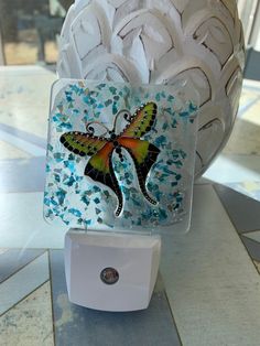 a glass sculpture with a butterfly painted on it's side and an outlet in the middle