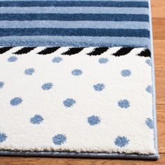 a blue and white area rug with polka dots on the bottom, in front of a wooden floor