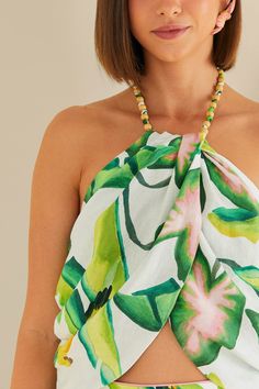 Embrace the tropical vibe with the Summer Foliage Off White Croped Top by FARM Rio. This halter neckline top features a vibrant leafy pattern, evoking the lush landscapes of Brazil. The delicate ruffles and eyelet fabric add a touch of femininity to the piece, while the cropped silhouette keeps it modern and fresh. Perfect for a summer day out, this top will bring a playful and stylish flair to your wardrobe. Composition 55% LINEN 45% VISCOSE Care Instructions MACHINE WASH GENTLE CYCLE, DO NOT B Summer Tropical Print Halter Top Beachwear, Summer Tropical Print Halter Top For Beachwear, Summer Beachwear Halter Top With Tropical Print, Chic Tropical Print Tops For Beach, Tropical Halter Top For Vacation, Summer Tropical Print Halter Top For Beach, Beachwear Halter Top With Tropical Print, Beachwear Tropical Print Halter Top For Beach, Tropical Halter Top For Beach Vacation