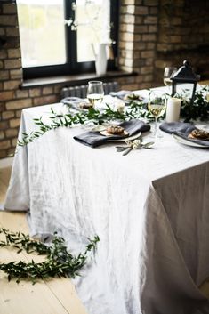 the table is set with place settings and greenery