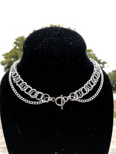 This is a shorter double stranded necklace that features a t bar closure in the middle of the necklace. The top strand is a chainmaille weave made with 10mm diameter jump rings. The entire necklace is made of 304 Stainless Steel. The top strand is about 15 inches.   Stainless steel is a great material for jewelry - it's tarnish and rust resistant, it's hypoallergenic (good for sensitive skin/ won't discolor your skin); it will last. To clean this piece just use some soap/water and a thorough dry, or dry it off after showering with it on. Metal Lariat Necklace With Double Chain, Metal Lariat Choker With Adjustable Chain, Adjustable Metal Chain Choker, Handmade Sterling Silver Chain Choker, Silver Double Chain Lariat Necklace, Silver Lariat Necklace With Double Chain, Double Strand Metal Necklace With Silver Chain, Handmade Double Strand Metal Jewelry, Adjustable Lariat Chain Necklace In Metal