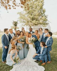 a group of people standing around each other in front of a tree and grass field